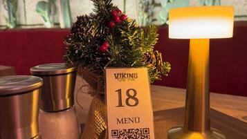 A table with a menu sign, a decorative plant, and a table lamp.