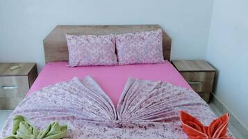 A bed with a pink bedspread, two pillows, and a decorative book arrangement on the bed.