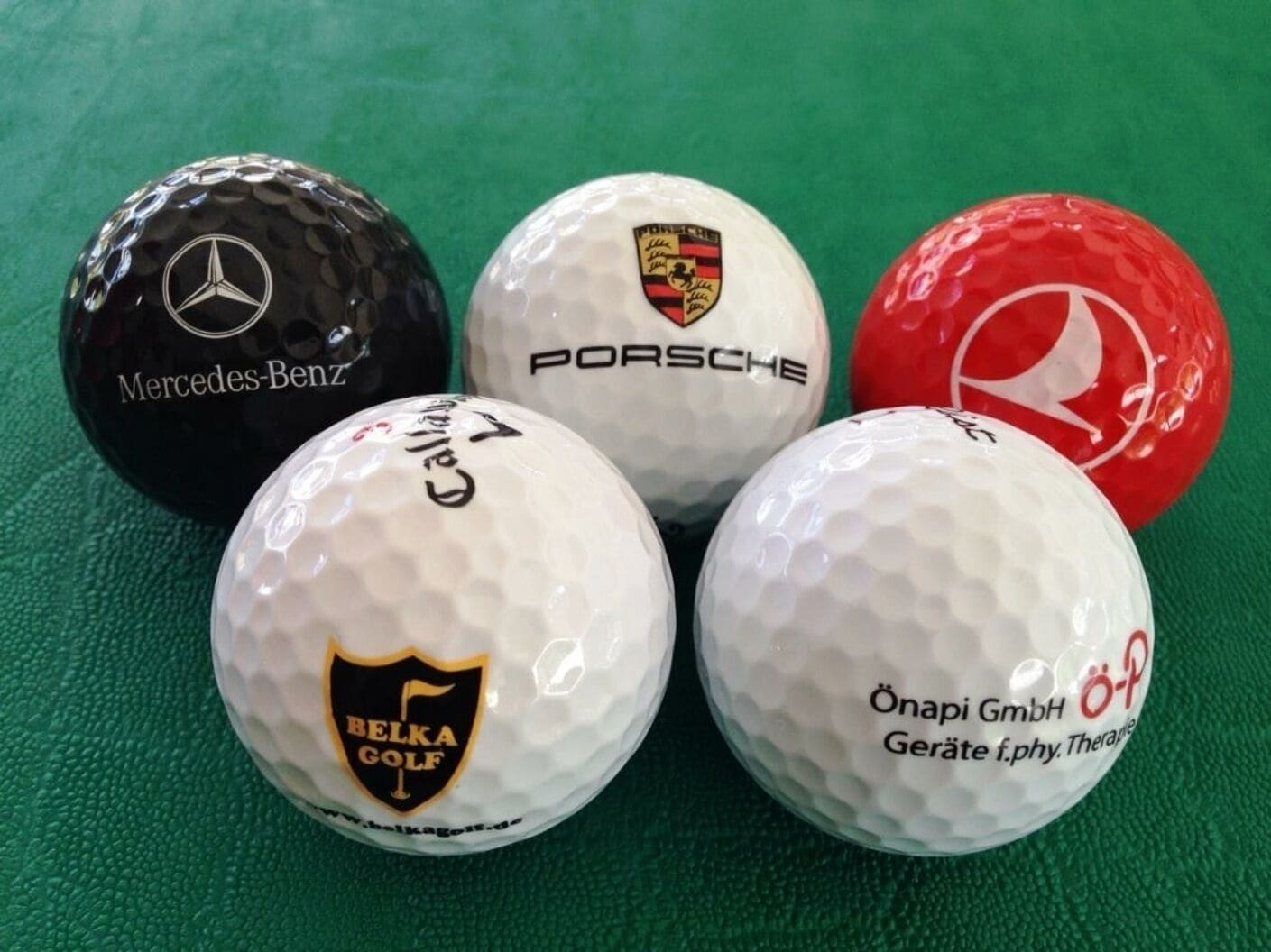Cinco pelotas de golf con diferentes logotipos de marca.