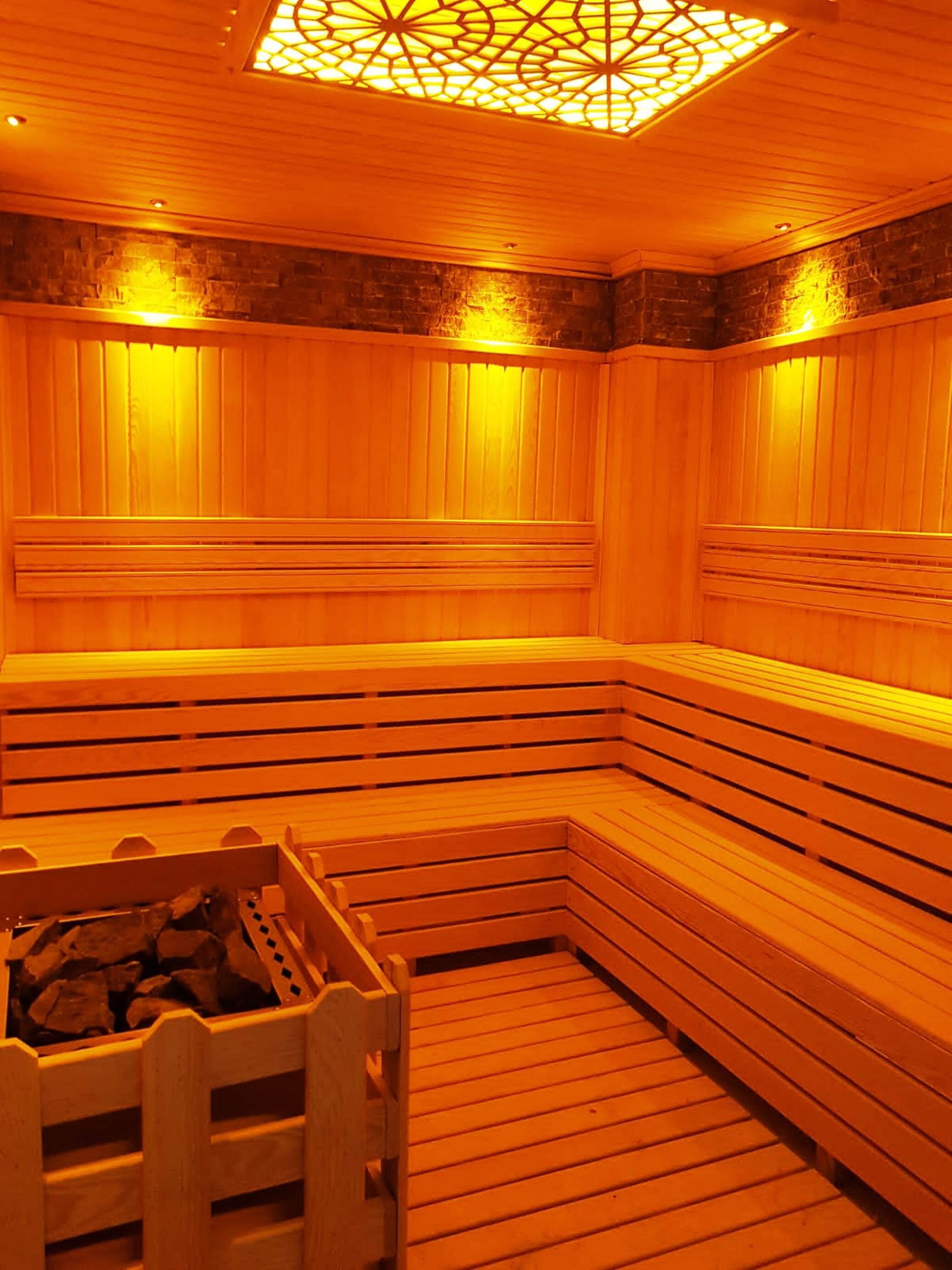 Una sauna con bancos de madera y un hogar central.