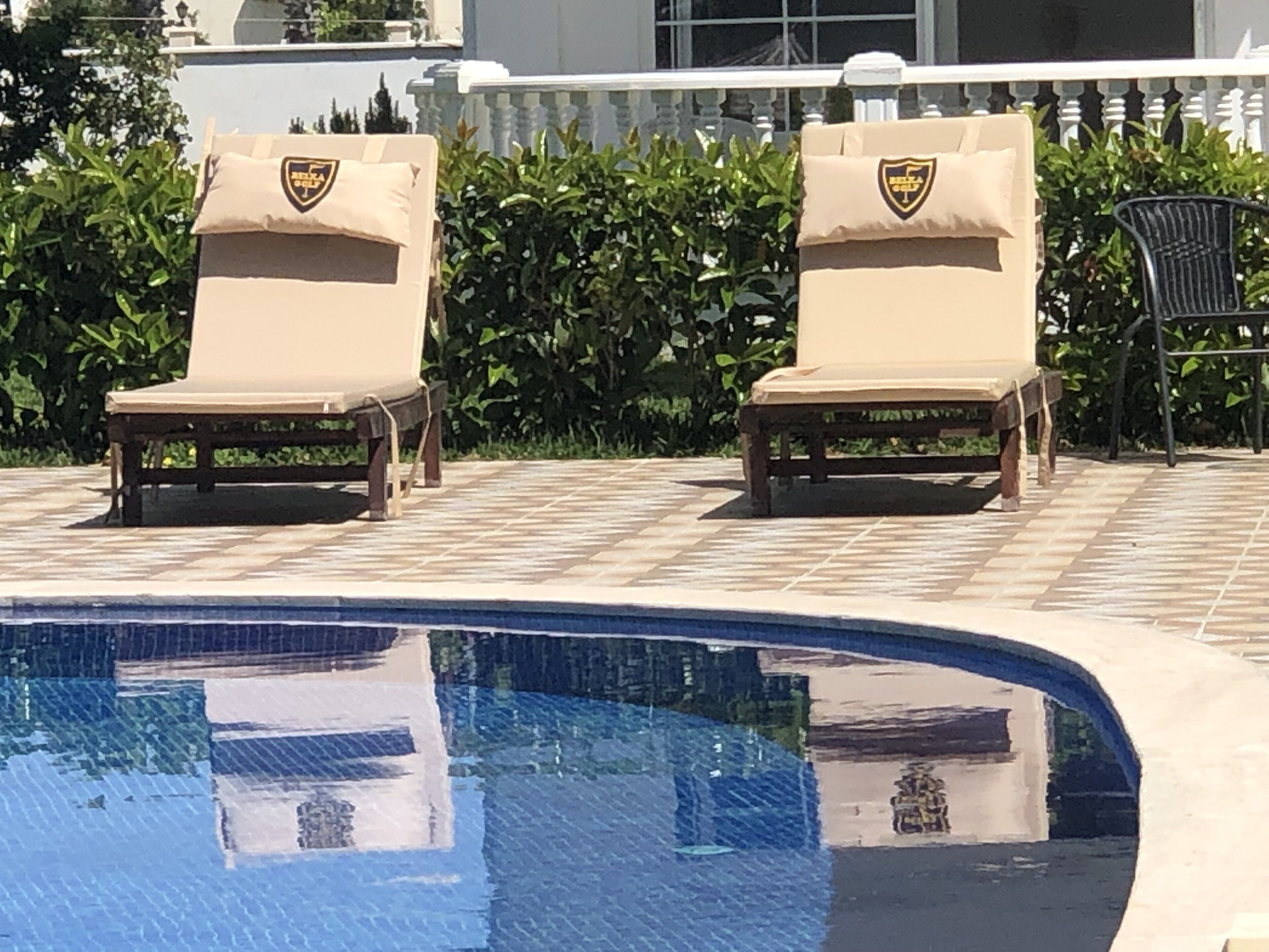 Ett poolområde med två solstolar och en pool.