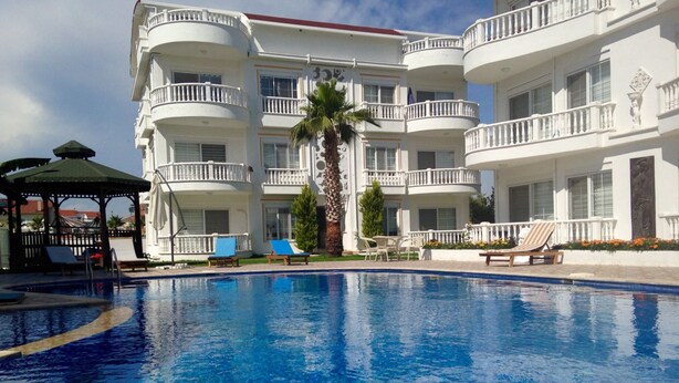 A hotel with a large swimming pool, multiple balconies, and a gazebo. - Belka Golf Residence (Serik)