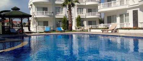 Una piscina al aire libre, sombrillas, tumbonas