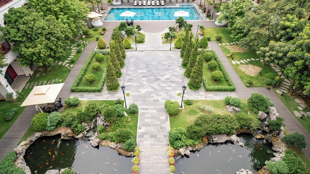 A rooftop pool area with a central water feature, surrounded by neatly trimmed hedges and pathways. - Senna Hue Hotel (Hue)