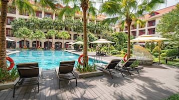 Una piscina al aire libre, sillones reclinables de piscina