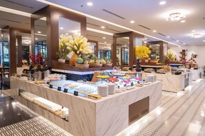 A buffet area with marble counters, various food items, and decorative plants. - Senna Hue Hotel (Hue)