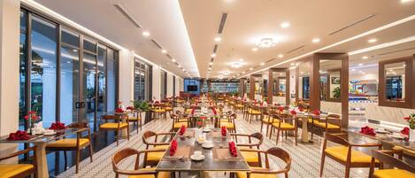 A spacious dining area with long tables, yellow chairs, and red napkins.