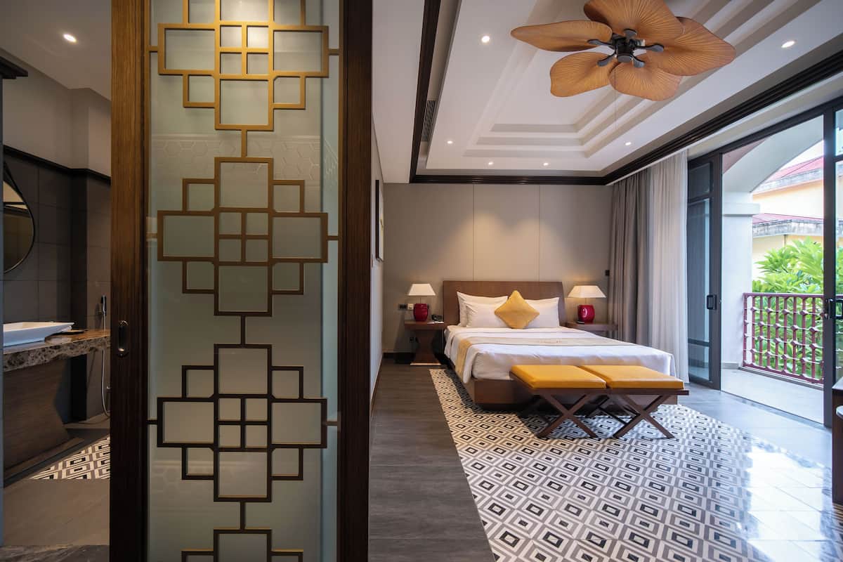 A modern hotel room with a large bed, bedside lamps, a wooden headboard, and a balcony with a view.