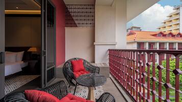 A balcony with wicker furniture, a small table, and a view of a hotel building.