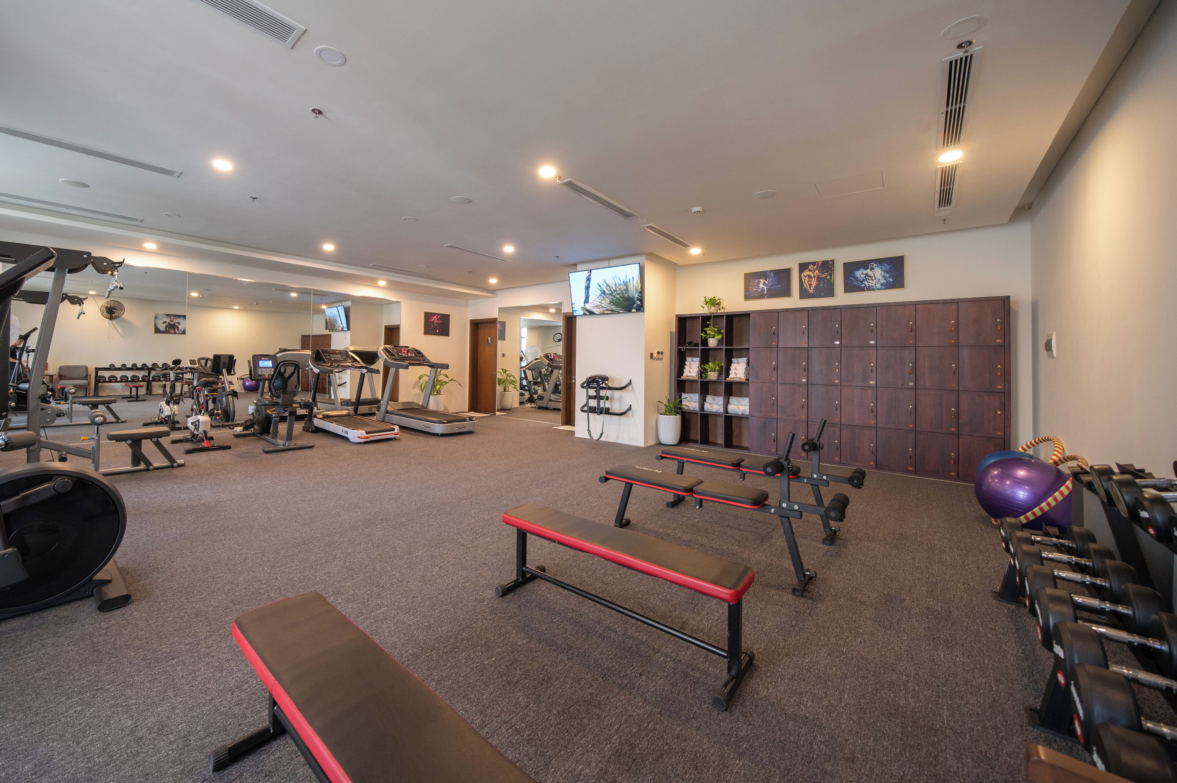 A gym with exercise equipment, benches, and lockers.