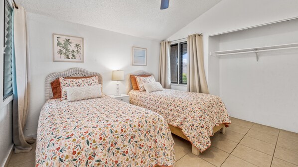 Un dormitorio con dos camas, una ventana con cortinas, un estante en la pared y un cuadro enmarcado.
