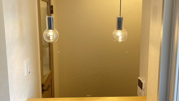 A hallway with two hanging light bulbs, a wooden floor, and a door. - Popular Makiminato (Urasoe)