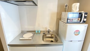 A compact kitchenette with a stainless steel sink, a microwave, and a refrigerator. - Popular Makiminato (Urasoe)