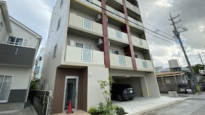 A multi-story residential building with a parking garage. - Popular Makiminato (Urasoe)