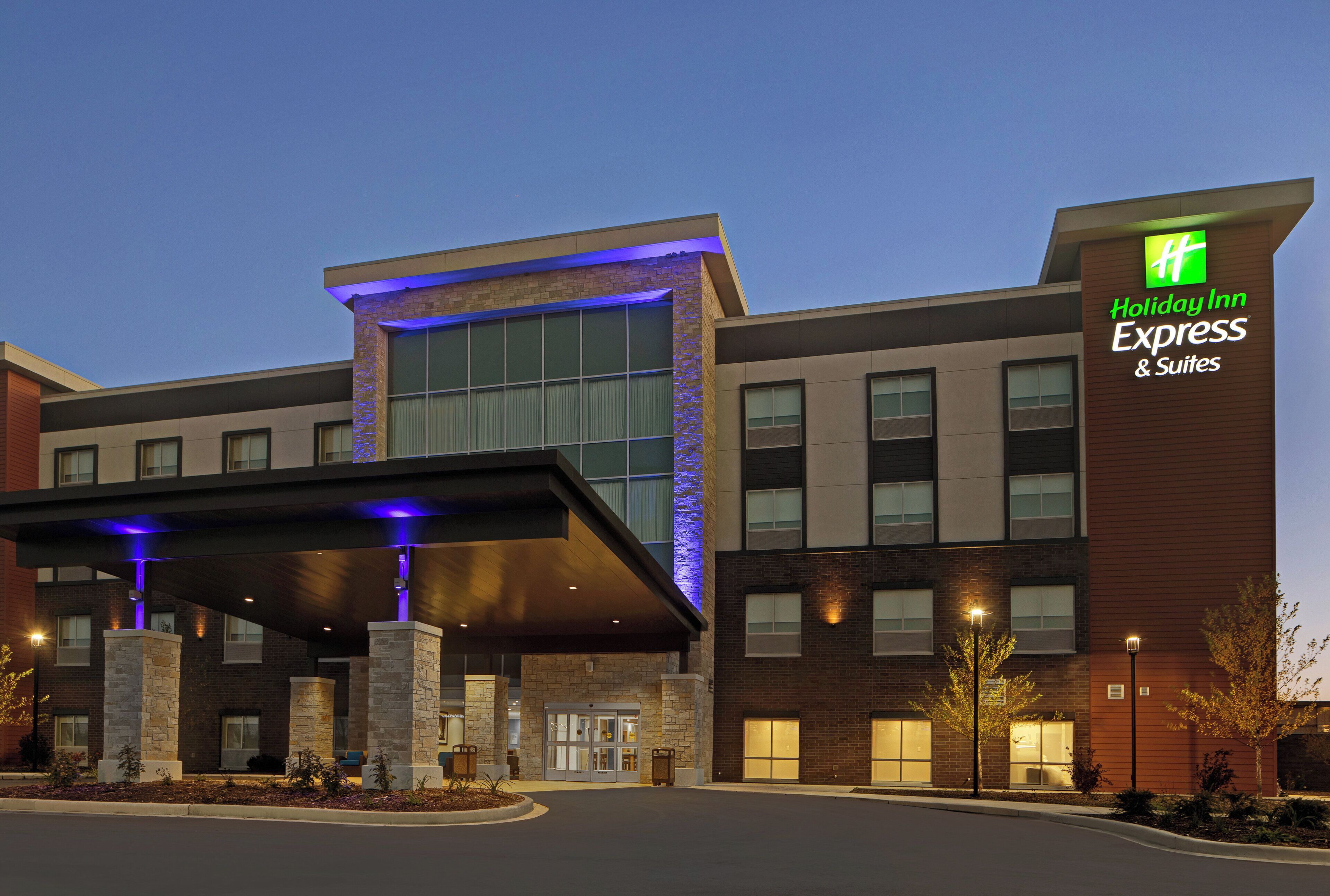 Un hôtel Holiday Inn Express & Suites au design moderne, doté d’une entrée imposante et d’un espace extérieur couvert.