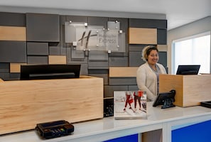 A reception desk with a Holiday Inn Express sign, a digital kiosk, and a welcome brochure.