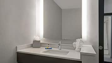 A modern bathroom with a large mirror, a white sink, and a towel rack.
