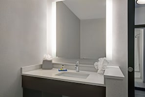 Een moderne badkamer met een grote spiegel, een witte wastafel en een handdoekrek.