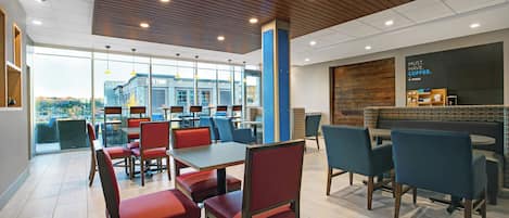 A modern cafe with tables and chairs, a large window, and a coffee station.