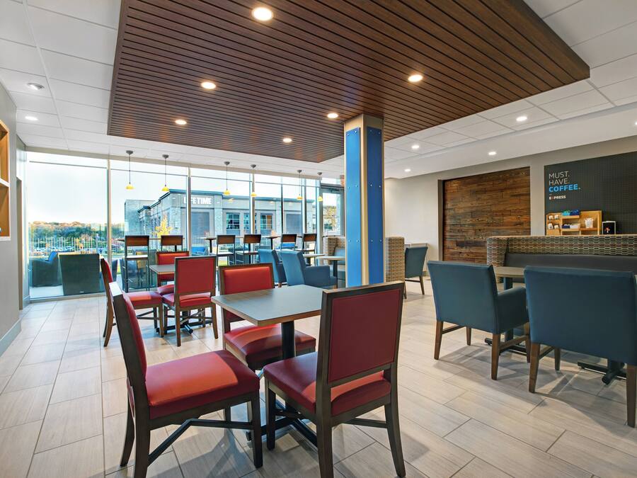 A modern cafe with tables and chairs, a large window, and a coffee station.