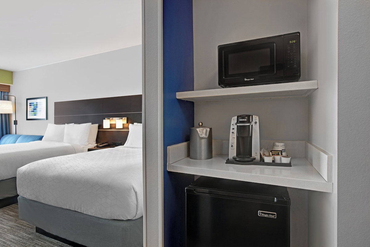 Een hotelkamer met een bed, een magnetron, een koffiezetapparaat en een koelkast.