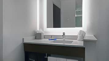 Un baño moderno con un espejo grande, un lavabo, un secador de pelo y un perchero para toallas.