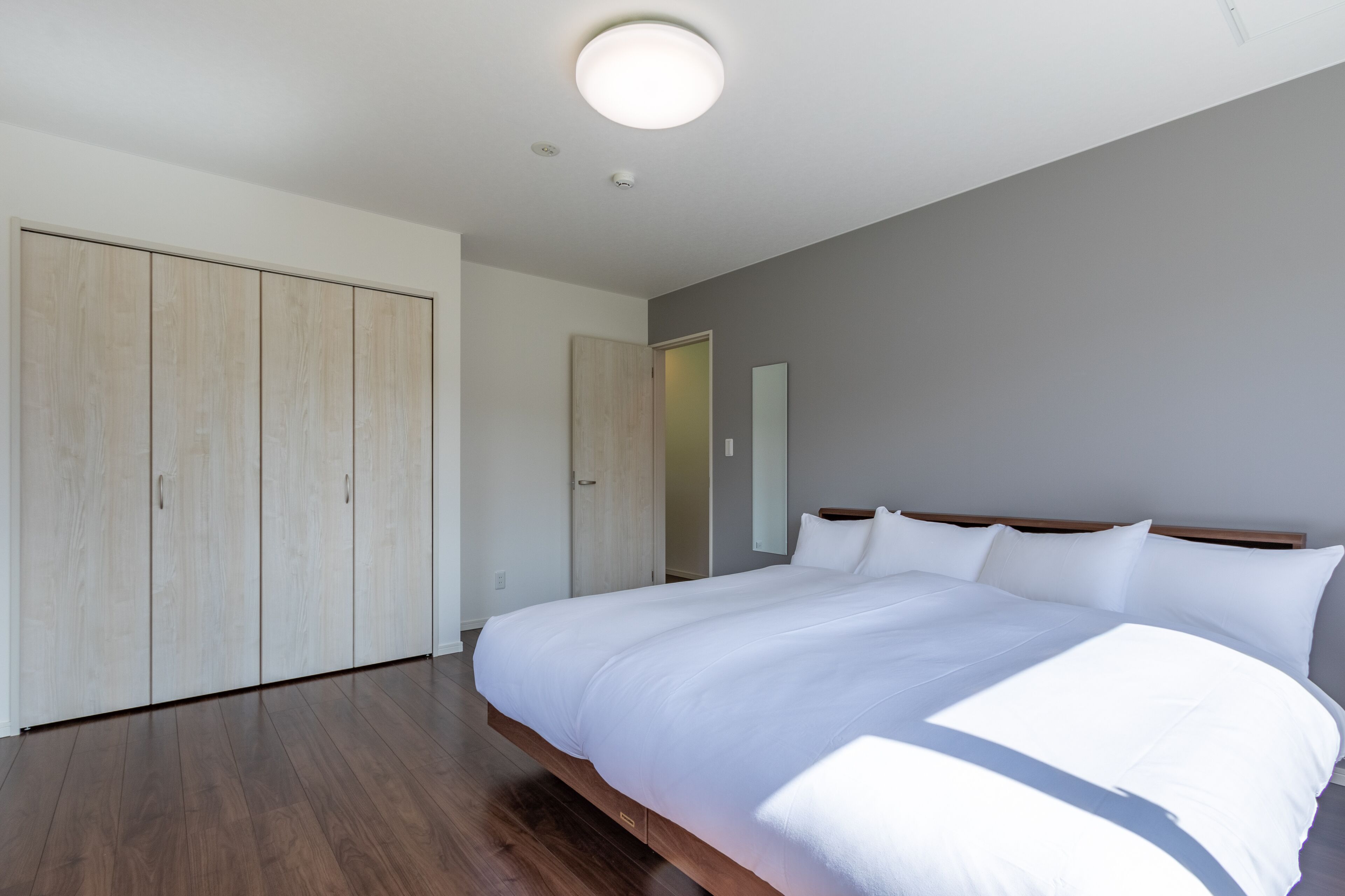 Ein Schlafzimmer mit einem großen Bett, einem Holzschrank und einer Deckenleuchte.