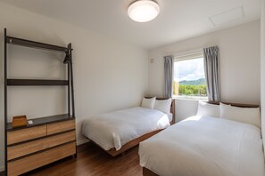 A bedroom with two beds, a wooden dresser, and a window with curtains. - Wapura Rusutsu (Rusutsu)