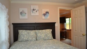 Ein Schlafzimmer mit einem Bett, einem Kopfteil und zwei an der Wand befestigten Kunstwerken.
