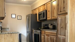 A kitchen with wooden cabinets, stainless steel appliances, and a granite countertop.