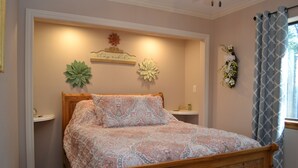 A bedroom with a wooden bed, a bedside table, a wall-mounted shelf, and decorative wall art.