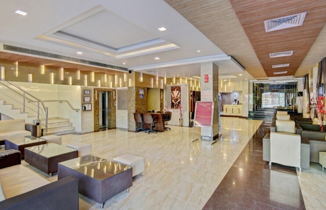 A spacious lobby with a central staircase, seating areas, and a reception desk.