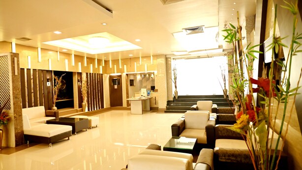 A modern lobby with a reception desk, seating area, and a staircase leading to upper floors. - Citi Club (Kanpur)