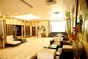 A modern lobby with a reception desk, seating area, and a staircase leading to upper floors. - Citi Club (Kanpur)