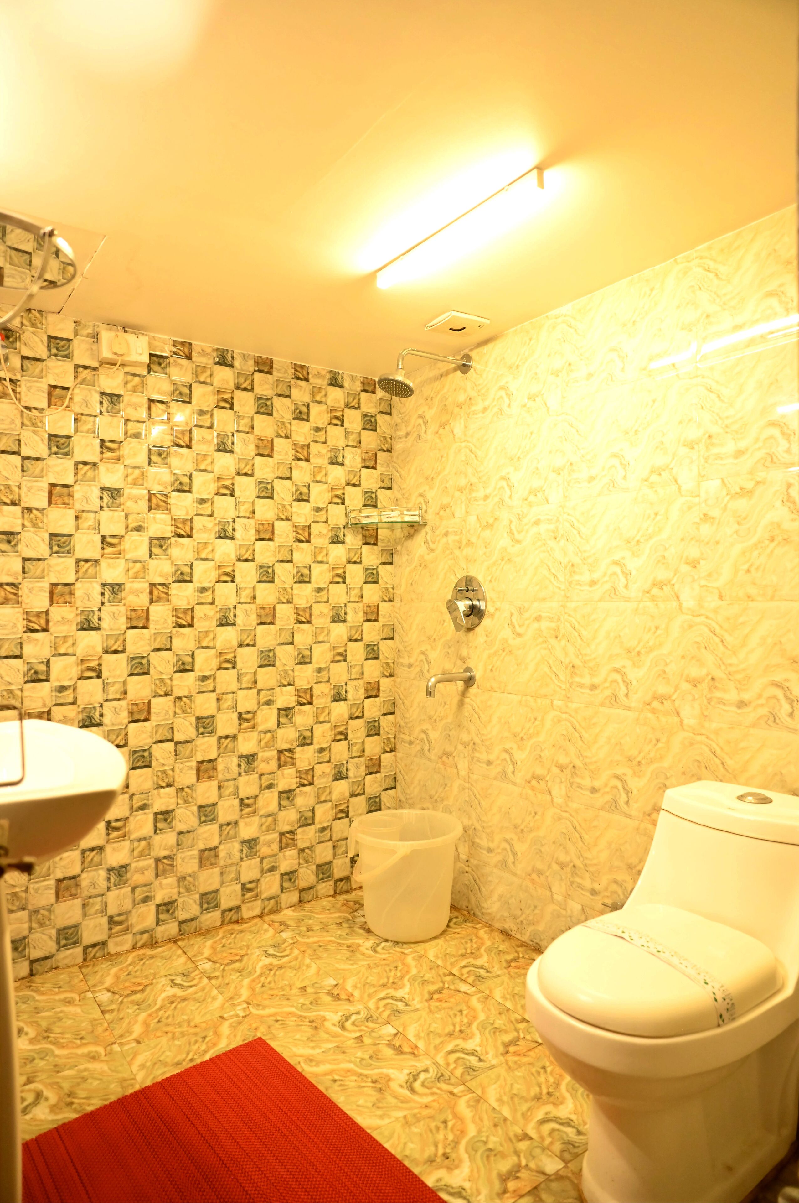 A bathroom with a patterned tile wall, a shower, a toilet, and a sink.