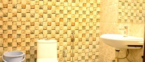 A bathroom with a tiled wall, a toilet, a sink, and a blue mat on the floor.