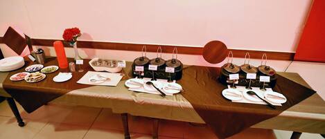 Mesa dispuesta con platos, cubiertos y recipientes etiquetados, probablemente para un bufé o evento de degustación.