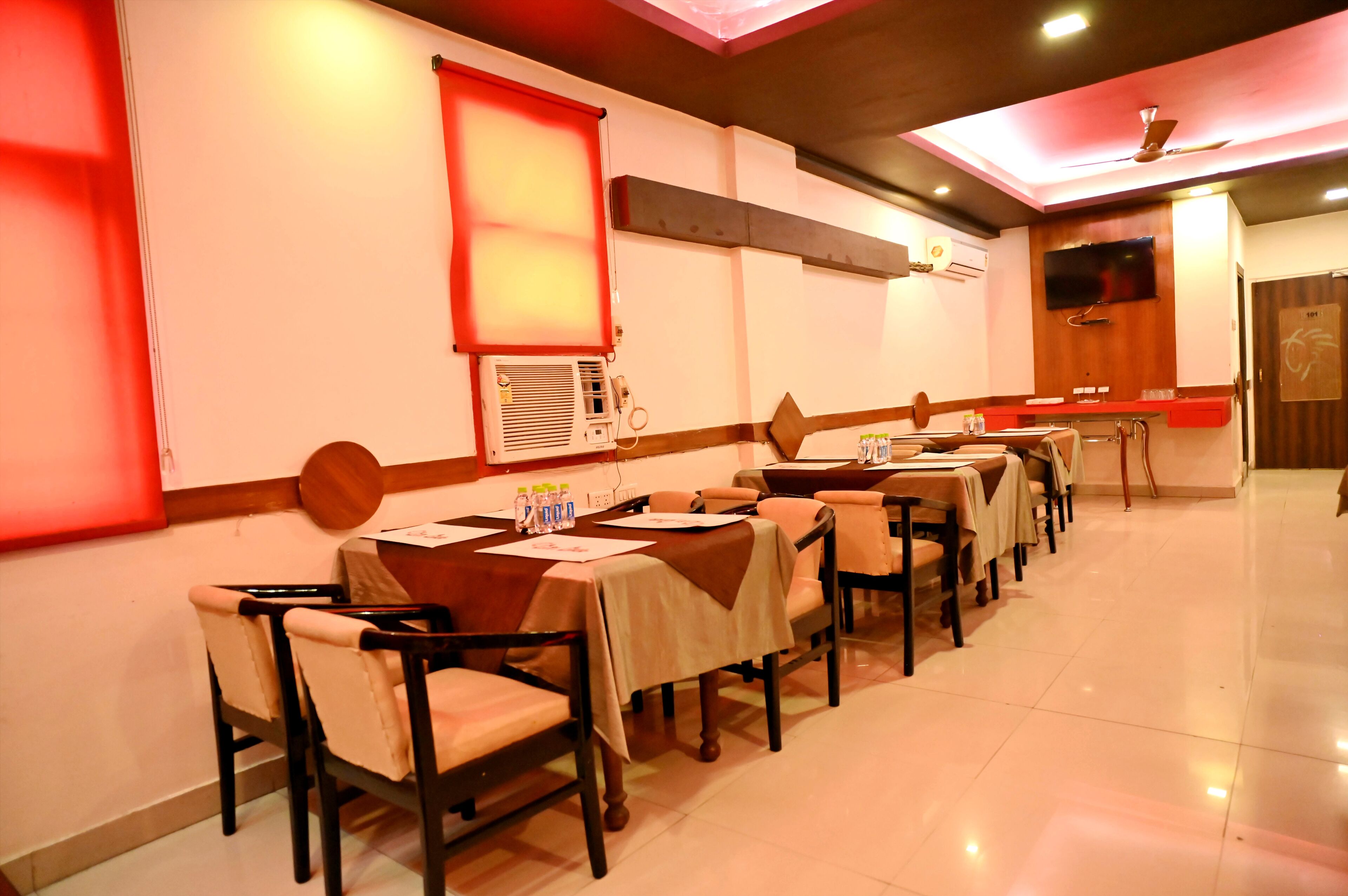 A dining area with tables and chairs, a ceiling fan, and a television mounted on the wall.