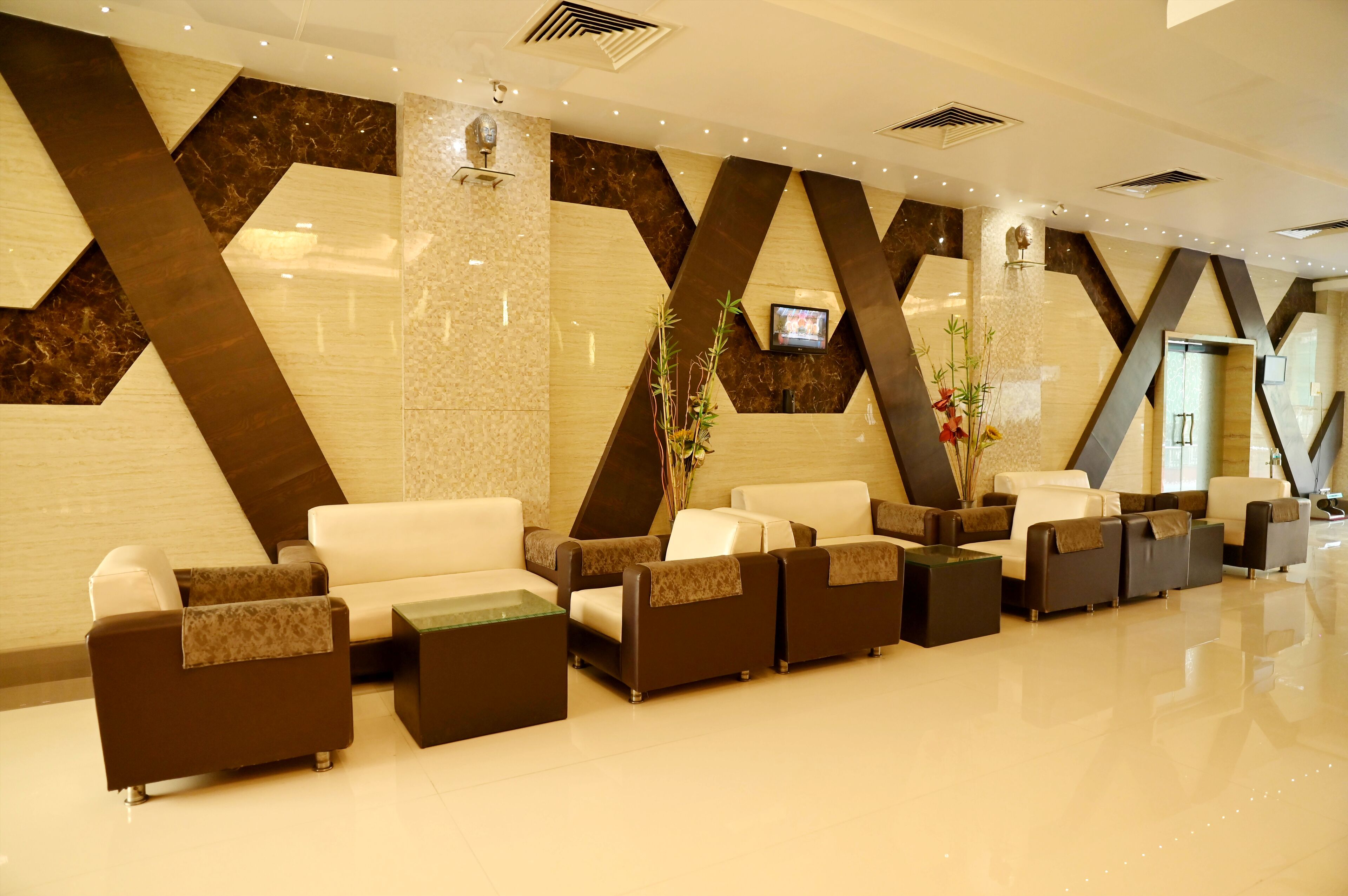 A modern lobby with a reception desk, seating area, and a TV mounted on the wall.