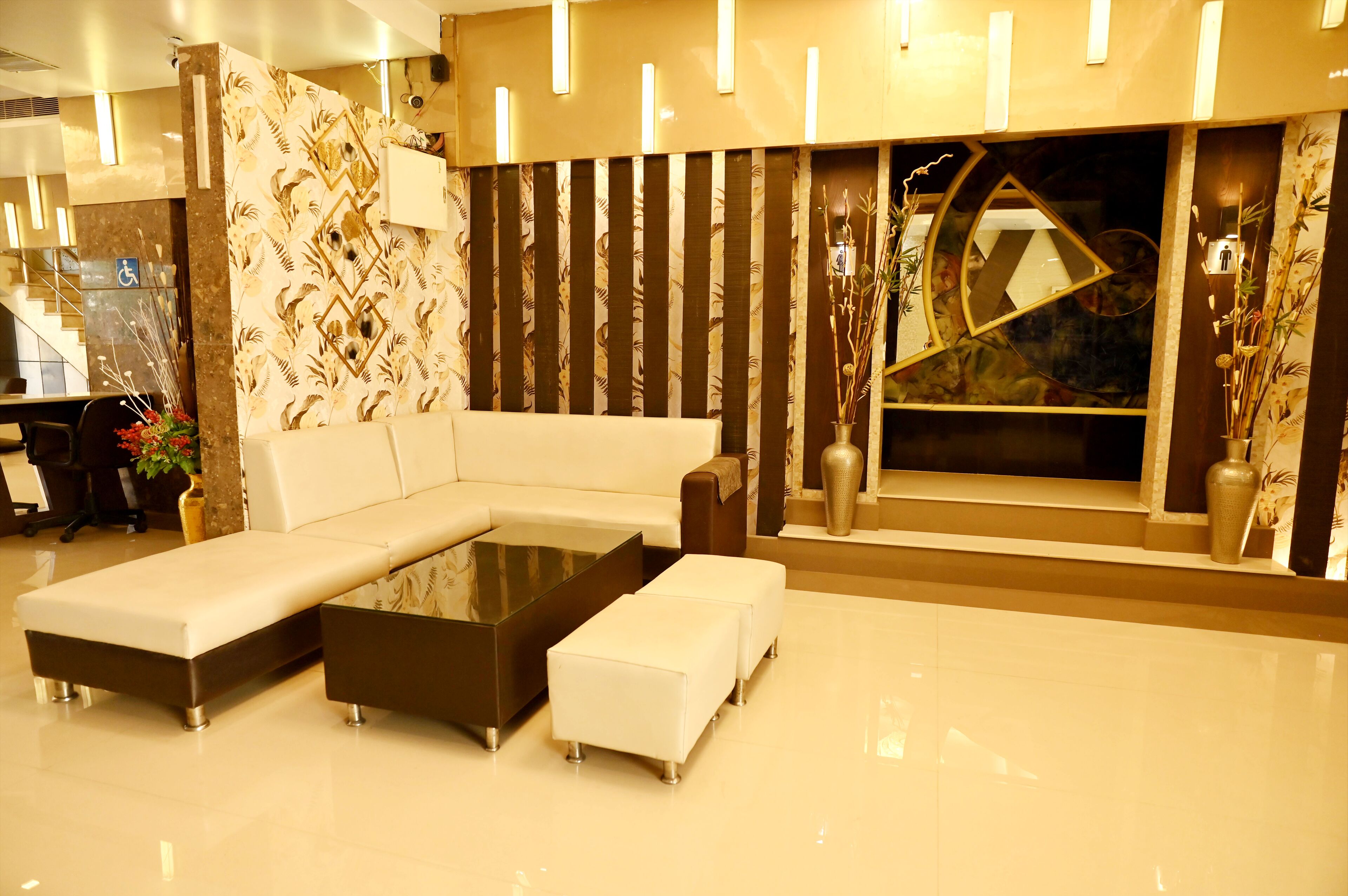 A modern lounge area with a sectional sofa, a glass coffee table, and a decorative wall with vertical panels.