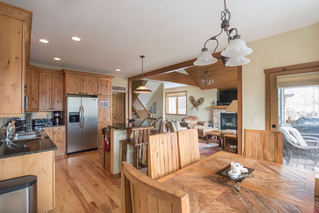 A spacious kitchen with wooden cabinets, a stainless steel refrigerator, and a dining area with a wooden table and chairs.