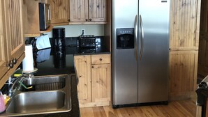 A kitchen with wooden cabinets, a stainless steel refrigerator, a sink, and a black countertop. - Walk to downtown Winter Park with views of Parry Peak (Winter Park)