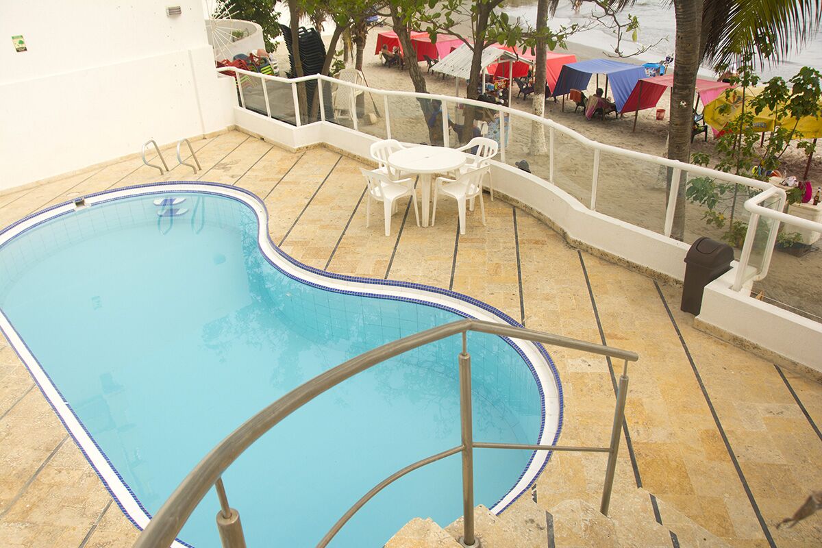 A swimming pool with a tiled deck, a white railing, and a table with chairs.