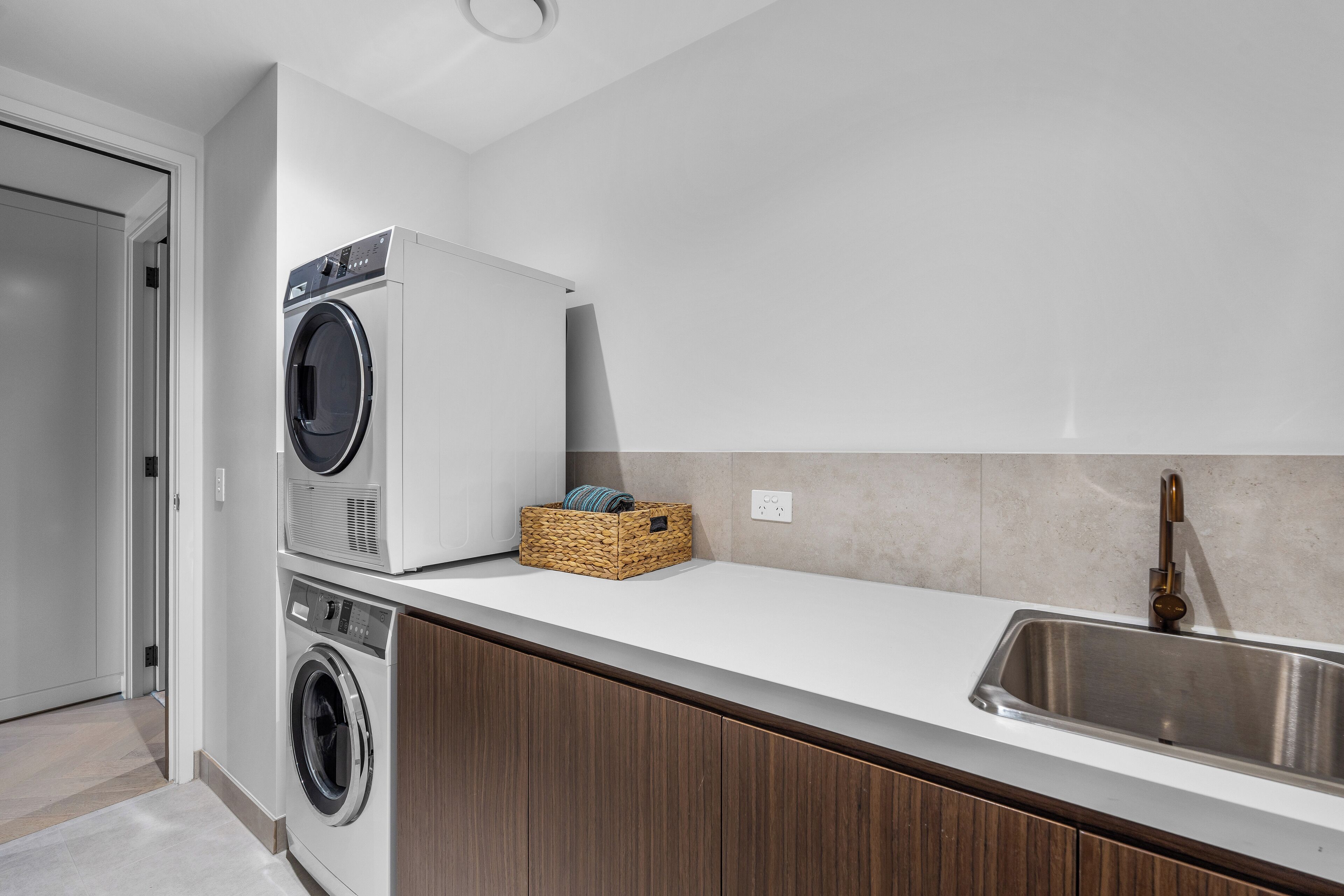 A modern kitchen with a built-in washer and dryer, a stainless steel sink, and wooden cabinets.