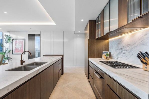 A modern kitchen with a large island, stainless steel appliances, and wooden cabinetry.