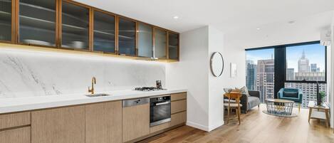 A modern kitchen with a marble countertop, wooden cabinets, and a built-in oven.