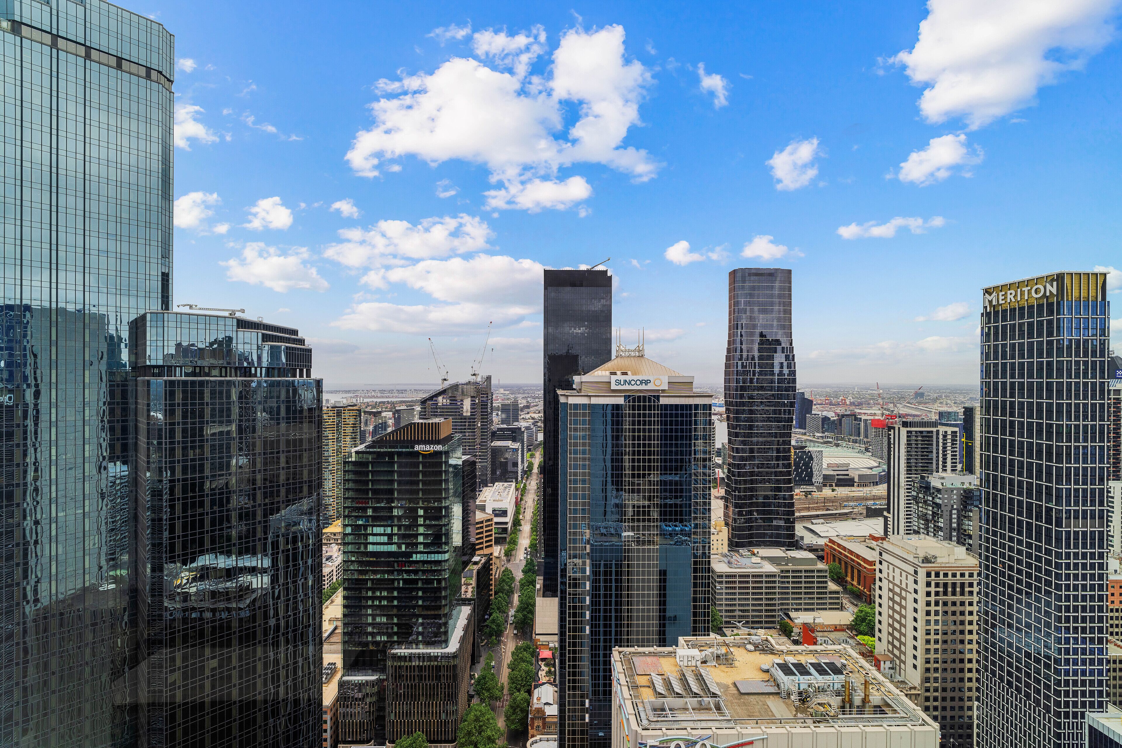 A high-rise urban skyline with modern glass buildings, including a prominent Suncorp building.