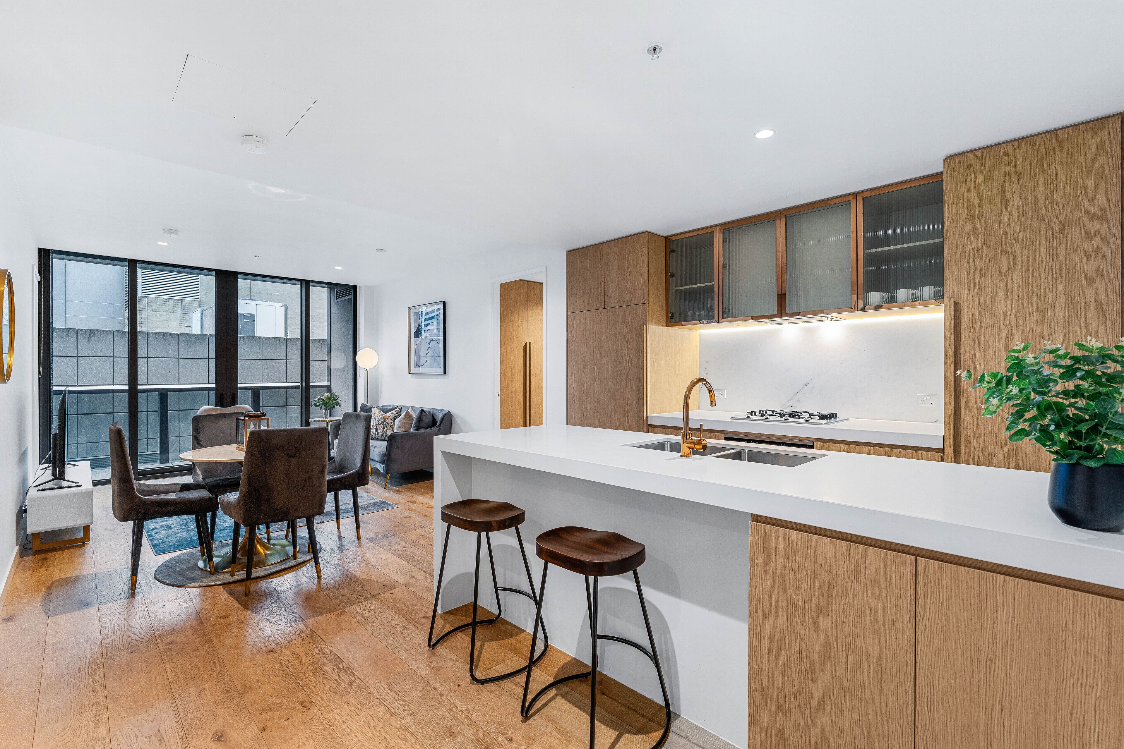 A modern kitchen with a white countertop, wooden cabinets, and a large window.