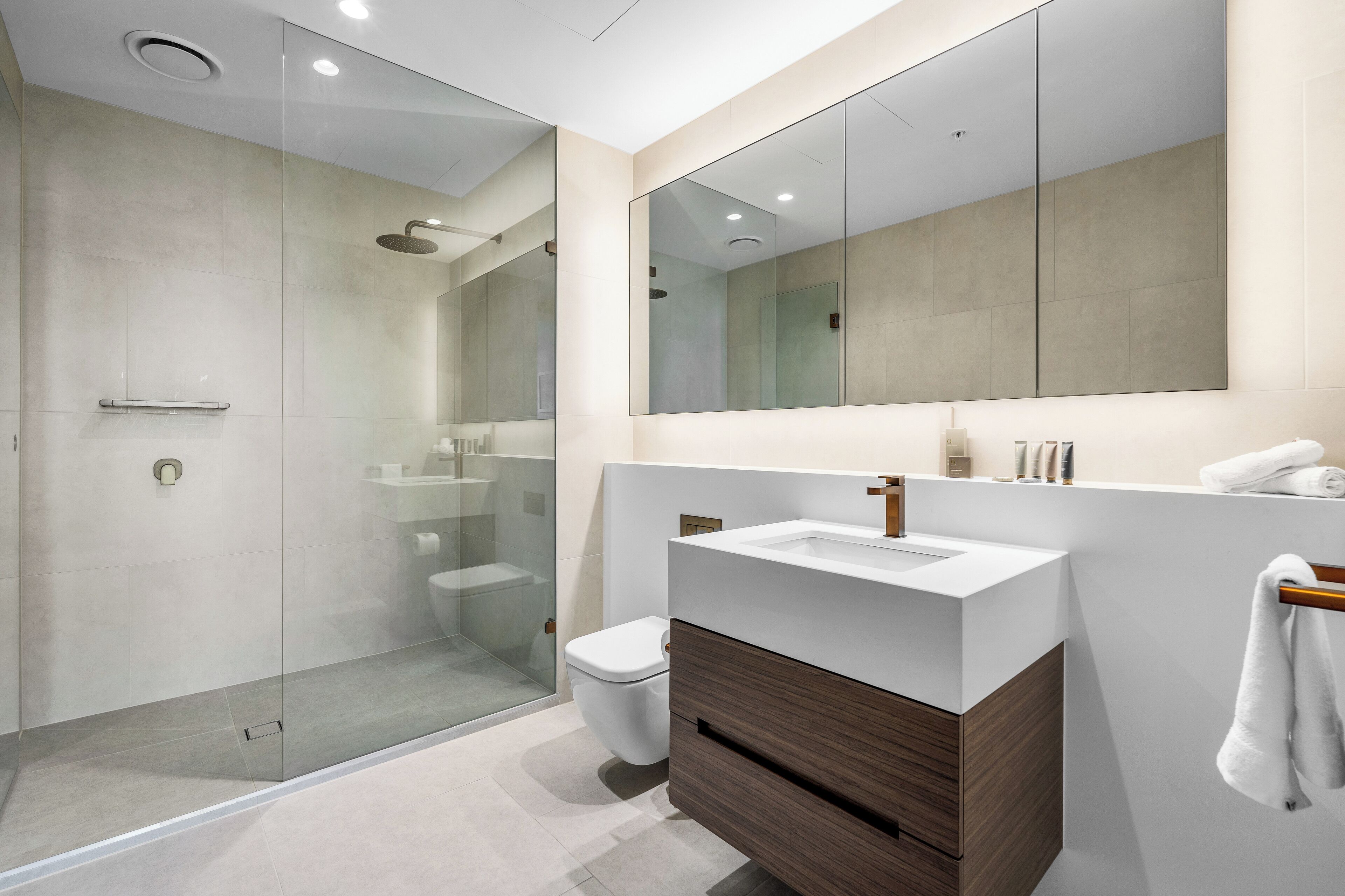 A modern bathroom with a glass shower enclosure, a white sink, and a large mirror.