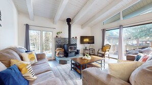 A cozy living room with a fireplace, comfortable seating, and a large window offering a view of the outdoors.